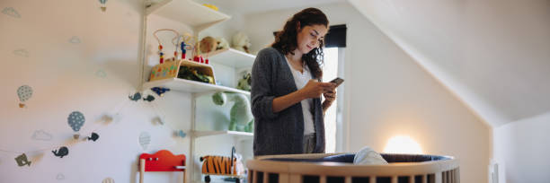istock Mother using cellphone after her baby gone asleep in the crib 1308963793
