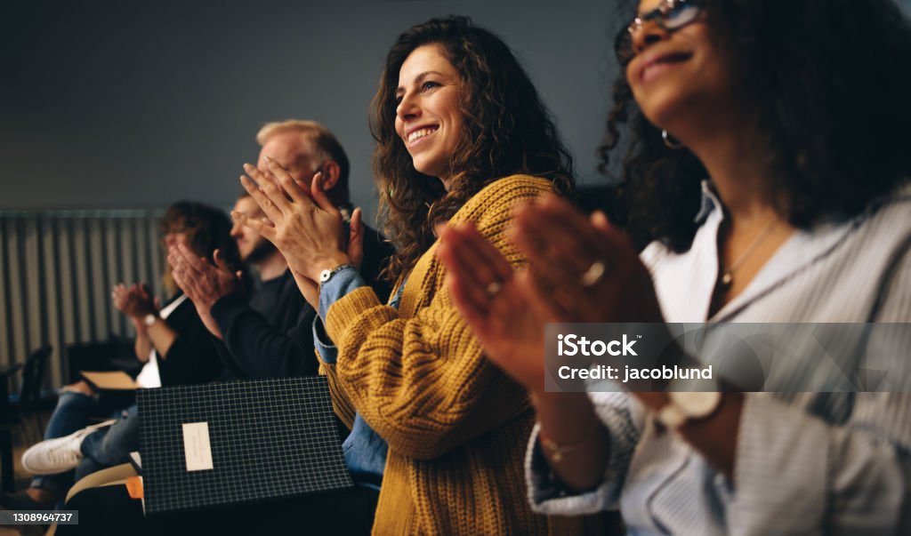 Business professionals applauding at a seminar Businesspeople sitting in audience and applauding. Group of multi-ethnic business professionals clapping hands while having a conference. Meeting Stock Photo