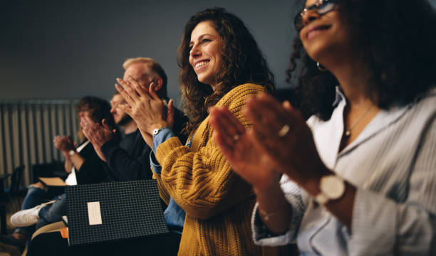 Business professionals applauding at a seminar Businesspeople sitting in audience and applauding. Group of multi-ethnic business professionals clapping hands while having a conference. auditorium stock pictures, royalty-free photos & images