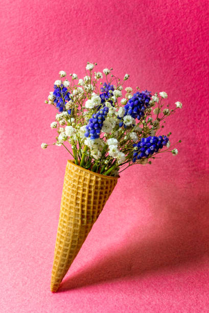istock Ice cream cone with flowers on pink background. Side view, copy space, spring flowers concept 1308965036