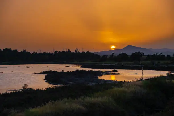 Sunset at the Larnaca salt lake in Cyprus witht he setting sun and wind turbines in the distance