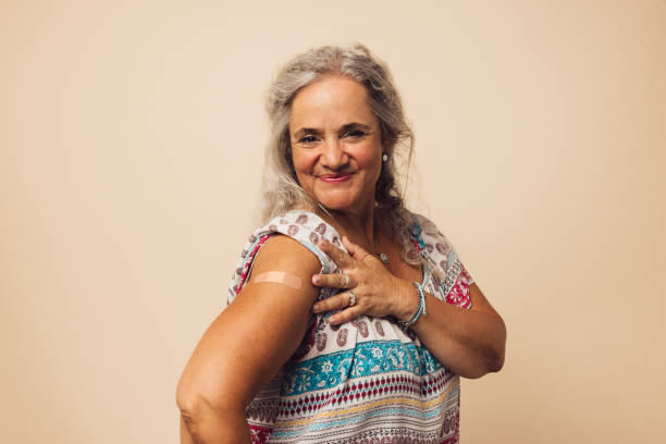 Feeling proud to get vaccinated Senior woman looking happy after getting vaccine. Elderly female showing her arm with a bandage after receiving vaccination. flu vaccine photos stock pictures, royalty-free photos & images