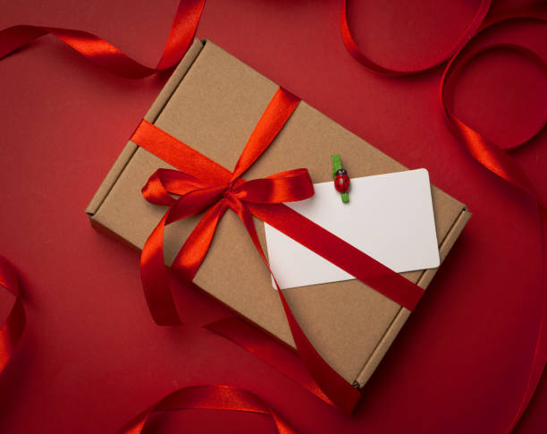 istock rectangular brown cardboard box tied with a silk red ribbon on a red background 1308968550
