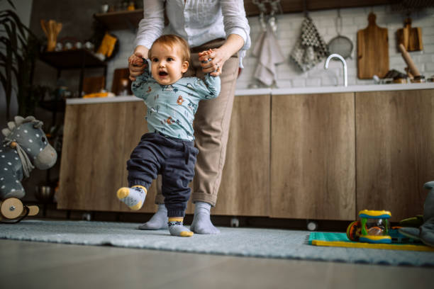istock Mother assisting her baby boy making first steps 1308976283