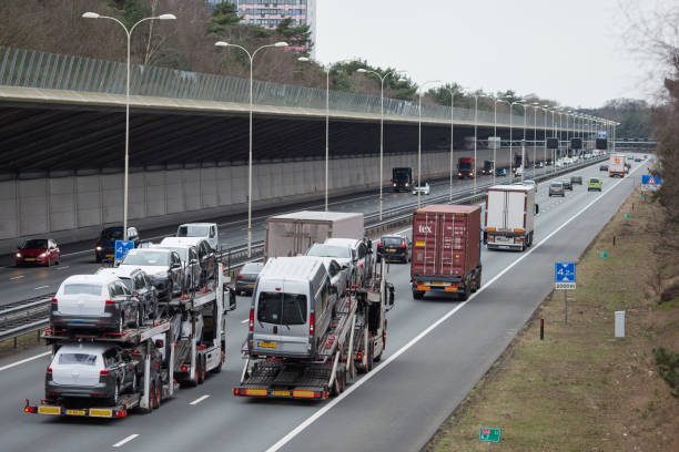 two car transporters and other traffic driving on dutch highway a-28 at zeist in daytime - personal land vehicle imagens e fotografias de stock