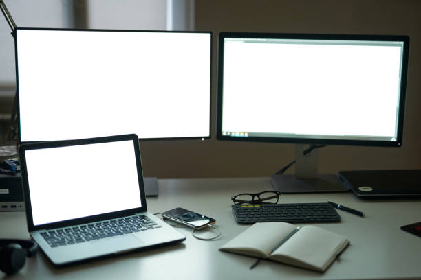 istock Many blank white screen of computer monitors with accessories and work tools on modern freelance working space 1308976865