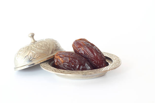 istock Dried palm date fruits in a silver bowl on white background. 1308977305