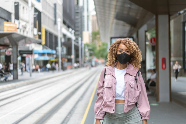 Gorgeous mixed race woman wearing protective face mask while commuting in city