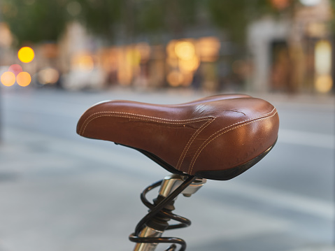 detail of a worn brown leather seat of a bicycle on a public street