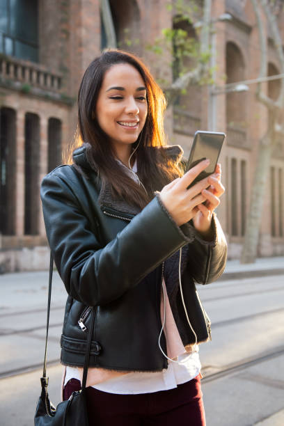 istock smiling young woman reading a message at her phone 1308983935
