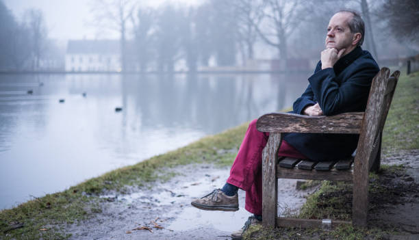 istock Leaning elbow on the park bench, a middle aged man alone in misty forest, lonely and abandoned in gloomy atmospheric mood 1308984042