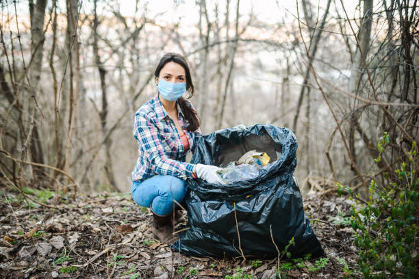 jovem colhendo resíduos plásticos na natureza. - mulher catando lixo - fotografias e filmes do acervo