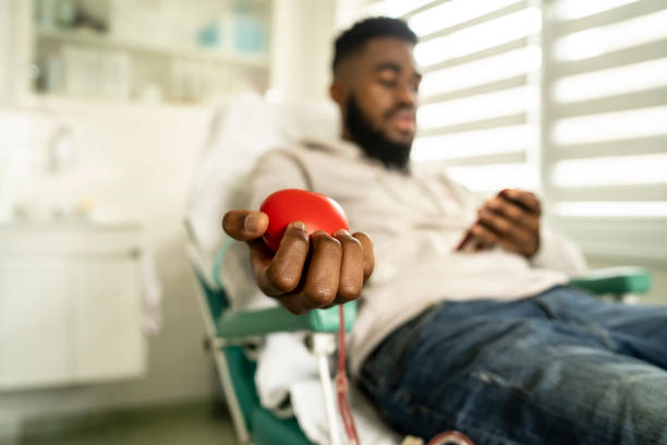 Young man donating blood African-American man donating blood for charity blood plasma stock pictures, royalty-free photos & images