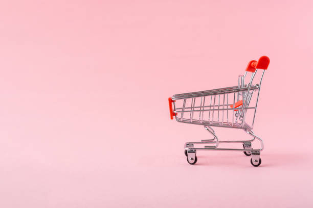 istock Shopping trolley on light pink background with a copy space. 1308985952