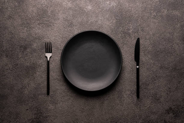 istock black empty plate and cutlery, fork and knife, on a dark textured background. Mockup concept for the design of a restaurant menu, website or design 1308992829