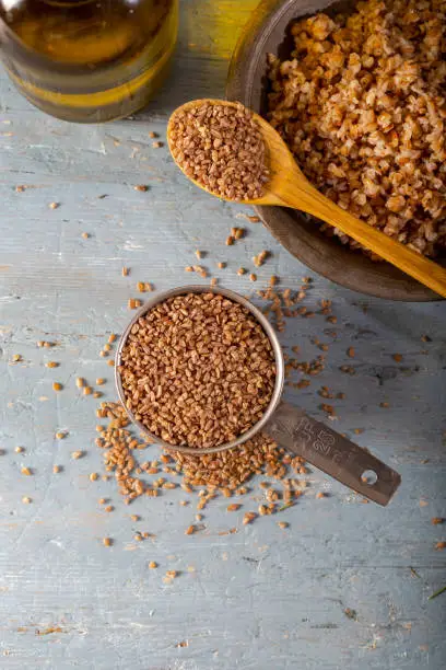 Siyez bulgur in metal measuring bowl on blue wooden table. (Einkorn bulgur)