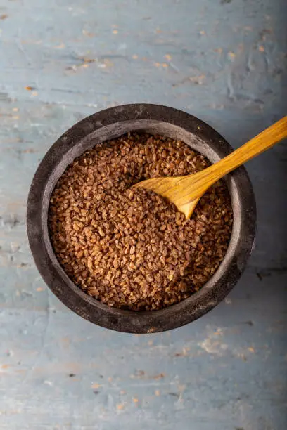 Siyazan bulgur (einkorn) in stone mortar on wooden background.