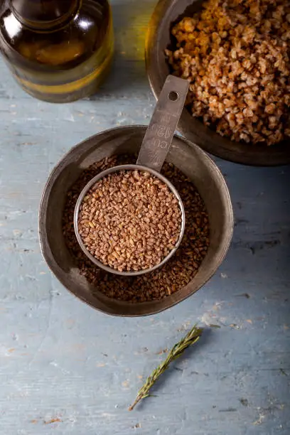 Siyez bulgur in metal measuring bowl on blue wooden table. (Einkorn bulgur)