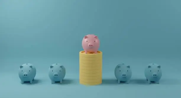 Photo of Pink piggy bank on coin stack standing out from crowd of identical blue fellows.