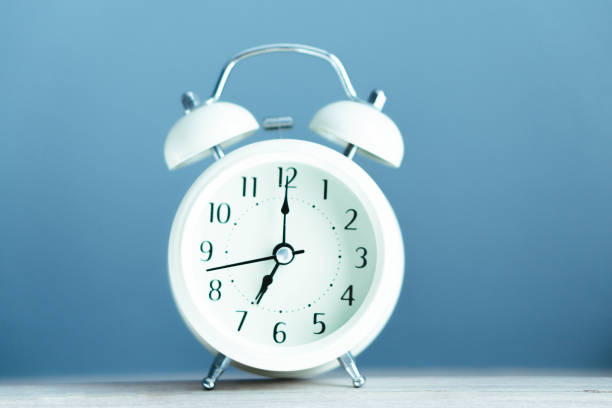 istock Alarm clock on blue table with soft light in the morning, selective 1309007085