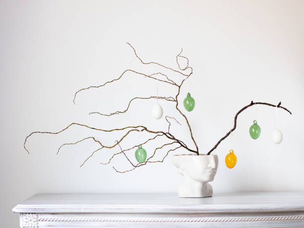 fotografia d'interni. foto creativa di un vaso a forma di testa di uomo con un ramo su cui pendono uova di pasqua colorate - easter ornament foto e immagini stock