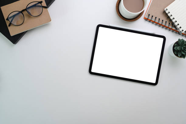 istock Overhead view of digital tablet, notebook, eye glasses and coffee cup on white table. 1309014944