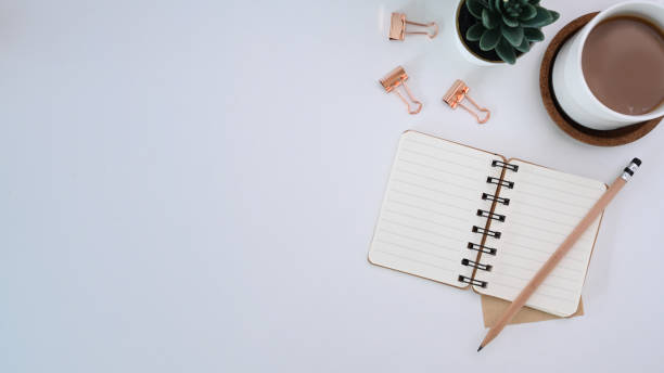 istock Top view of white office desk with empty notebook. pencil, coffee cup and copy space. 1309014997