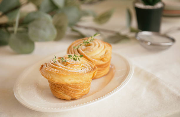 istock Homemade fresh baked cruffin sprinkle with icing or powdered sugar decorate with thyme leaf on white plate. Cruffin is a mixed of flaky layer croissant and muffin in muffin shape. Modern trend bakery. 1309017563