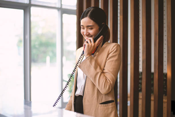 l'addetto alla reception dell'hotel stava rispondendo a una telefonata per fornire informazioni ai clienti. - receptionist foto e immagini stock