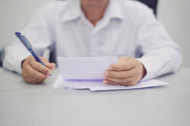 istock Mature businessman examining documents, the other hand holding a pen 1309018541