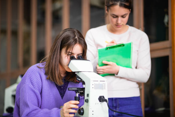 istock High school girls doing project for biology class, using microscope in lab 1309019568
