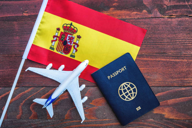 Flag of Spain with passport and toy airplane on wooden background. stock photo
