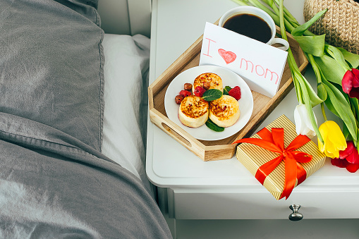 Delicious breakfast for holiday morning. Mother's day, birthday, 8 march, valentines day concept. Package gift box, colorful tulips, hot coffee, cottage cheese pancakes.
