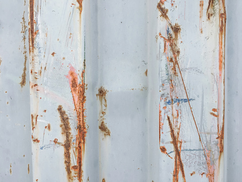 Close-up shot of white corrugated metal door texture with rusty scratches
