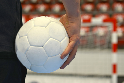 Closeup of a handballplayer holding a handball in front of the goal.