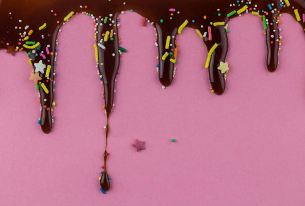 Chocolate dripping on pink background with dots, sprinkles and fun stars - text space for birthday invitation card