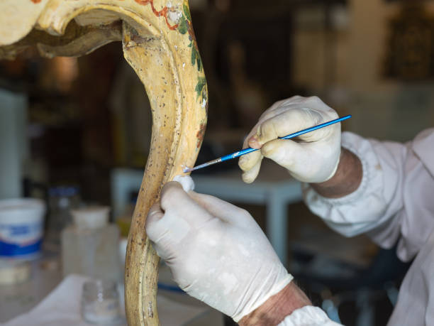 mani di un restauratore con guanti e pennello: lavorare al restauro di una sedia - restaurazione foto e immagini stock