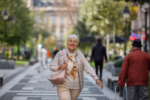 A Senior Woman is Walking in the Street, Exploring the City, and Going to Shopping Mall.