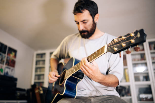 istock Young man practicing acoustic guitar at home.Focus selective.Enjoying music 1309025756