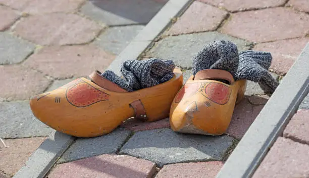 Old yellow wooden shoes with old socks at the side of a frozen river - Owner is ice skating - Common spectacle in dutch winter period