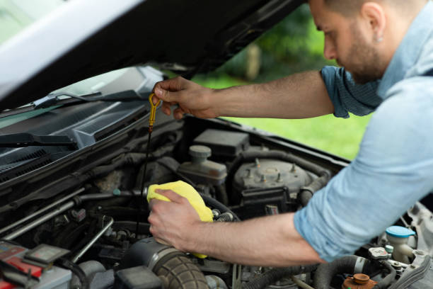mechaniker, der den ölstand eines motors in einem autohaus misst - vehicle breakdown hood car oil change stock-fotos und bilder