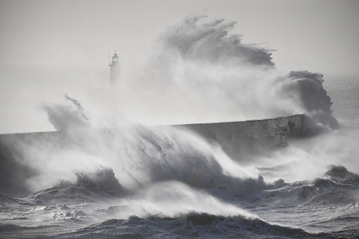 A storm in the English Channel sweeps over Newhaven harbour lighthouse\nLooks monochrome but is a colour image