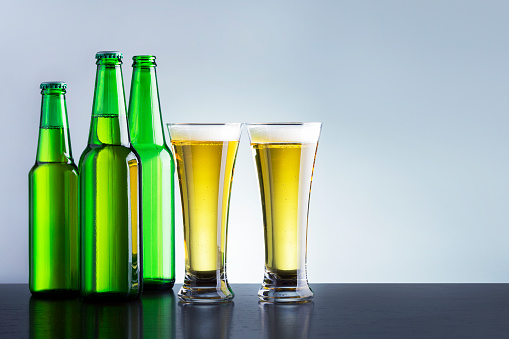 Wet beer bottles on rustic wooden background