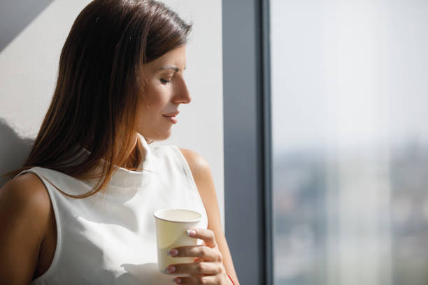 istock Young woman enjoying sunlight through office window on coffee break 1309033063