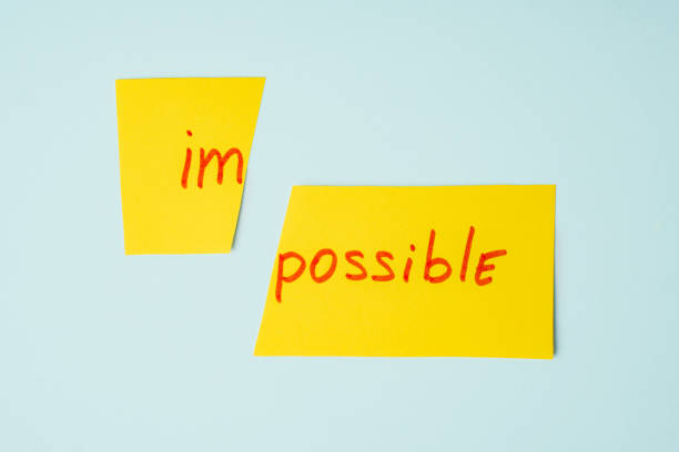 istock Scissors cutting paper with word IMPOSSIBLE on blue background. Impossible Is possible Concept 1309035253