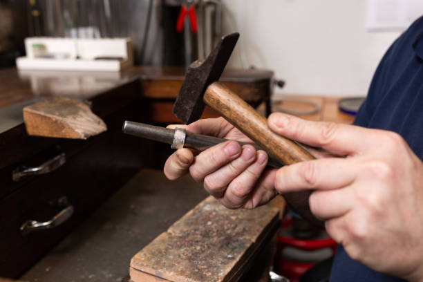 istock foreground, hammer hammering a silver ring to shape it in a jewelry workshop. 1309036723