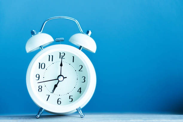 istock Alarm clock on blue table with soft light in the morning, selective 1309037522