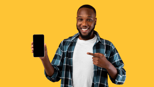 istock Black Guy Showing Smartphone Blank Screen Standing Over Yellow Background 1309037709