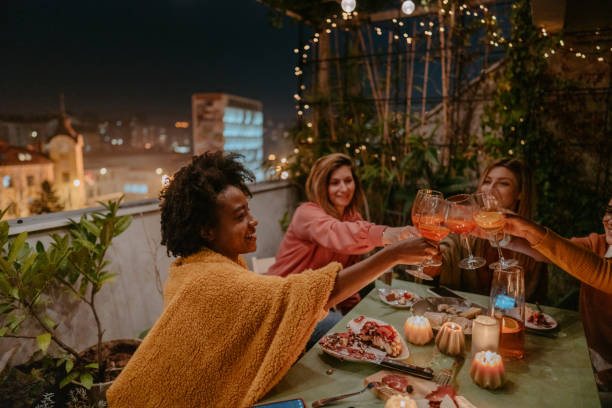 Celebrating with my girlfriends Photo of young women celebrating a birthday by drinking wine, eating cake, and enjoying each other's company while sitting on a terrace. dinner party stock pictures, royalty-free photos & images