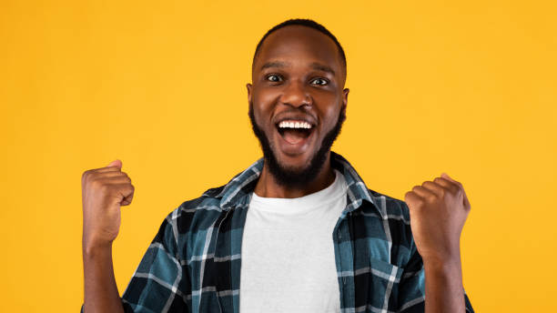 istock Excited African Guy Shaking Fists Posing Over Yellow Background, Panorama 1309039172